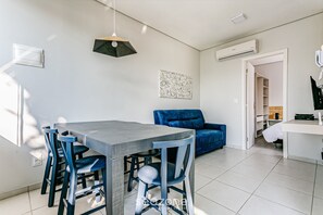 A modern living space with a dining area, a blue sofa, and a white desk. - Fit w/ Beautiful View of Lagoa da Conceicao Sdr002 (Florianópolis)