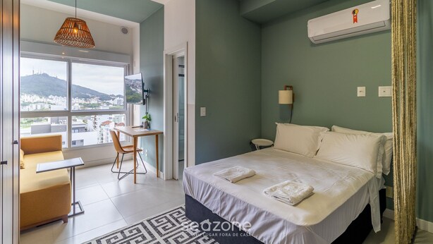 Habitación de hotel moderna con cama, escritorio y vistas de la ciudad.