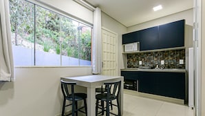 Una cocina compacta con comedor, ventana con cortinas y vistas al exterior a zonas verdes.