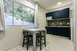 Una cocina compacta con comedor, ventana con cortinas y vistas al exterior a zonas verdes.