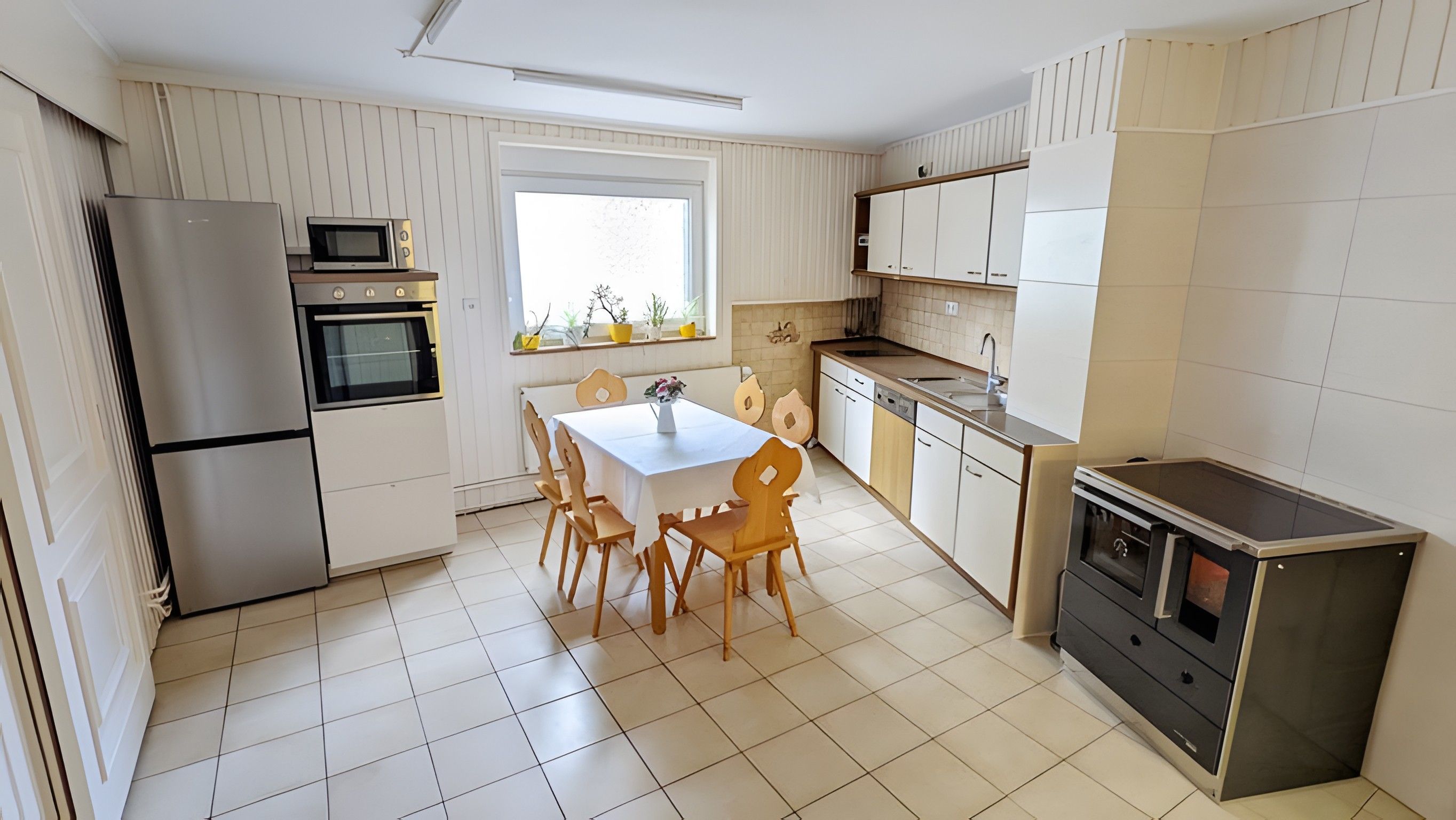 Eine kompakte Küche mit Essbereich, ausgestattet mit Kühlschrank, Backofen, Mikrowelle und Geschirrspüler.