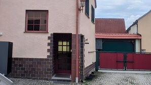 Ein zweistöckiges Gebäude mit rotem Ziegeldach, einem kleinen Fenster und einer roten Tür.