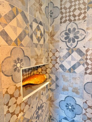 A bathroom with patterned tiles and a bread loaf on a shelf. - Casa Collazzi | Historic Center & Panoramic View (Montepulciano)