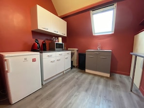 A compact kitchen with white cabinets, a microwave, and a refrigerator. - Beautiful apartment just a stone's throw from downtown, with a parking space (Blois)