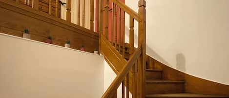 Un escalier en bois avec une rampe et une porte rouge en haut.