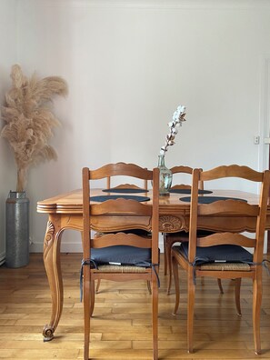 A wooden dining table with four chairs, a vase with a plant, and a tall decorative vase on the floor. - Beautiful apartment just a stone's throw from downtown, with a parking space (Blois)