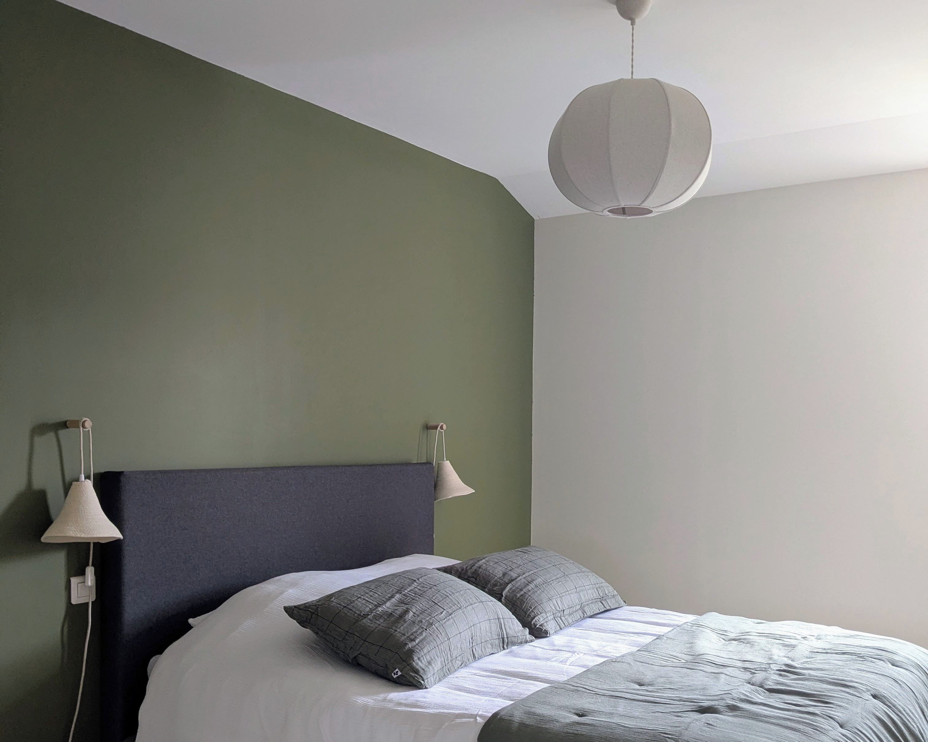 Une chambre à coucher avec un lit, deux lampes de chevet et un luminaire suspendu.