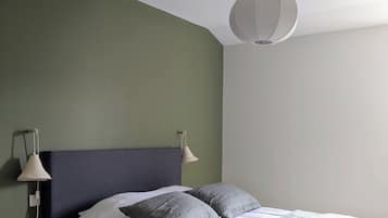 Une chambre à coucher avec un lit, deux lampes de chevet et un luminaire suspendu.