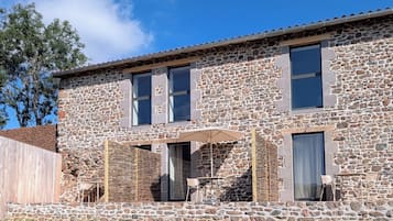 Un bâtiment en pierre doté d’un patio, d’un espace extérieur aménagé pour s’asseoir et offrant une vue sur le ciel.