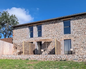 A stone building with a patio area, outdoor seating, and a view of the sky. - L'Atelier (Saint-Just-près-Brioude)
