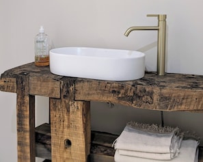 A bathroom with a rustic wooden vanity, a white sink, and a gold faucet. - L'Atelier (Saint-Just-près-Brioude)