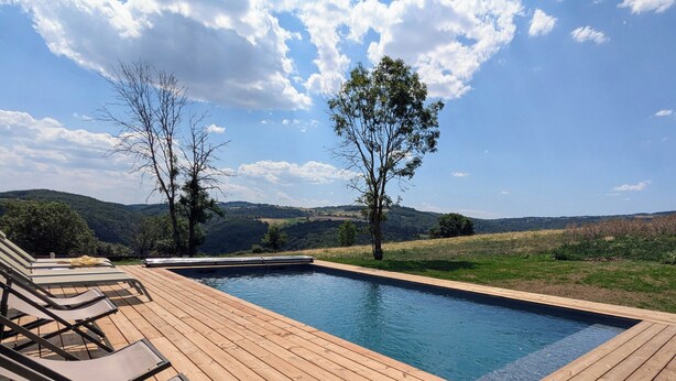 Una terrassa de fusta amb gandules i una piscina.