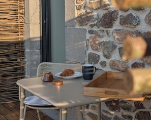 A table with a plate of food, a cup, and a jar, set against a stone wall. - L'Atelier (Saint-Just-près-Brioude)