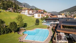 A residential area with a swimming pool, houses, and a mountainous backdrop.