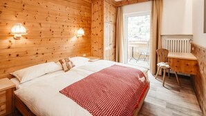 Ein Schlafzimmer mit Holzwänden, einem Bett, Nachttischlampen, einem Schreibtisch und einem Sessel.