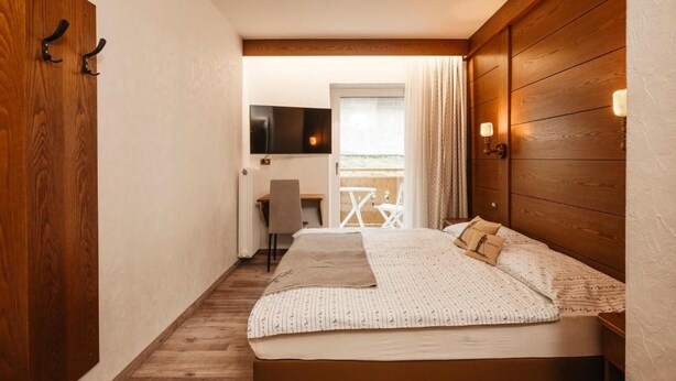 A bedroom with a bed, a desk, and a TV.
