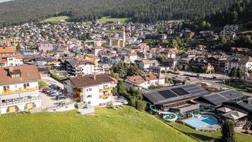 Un quartiere residenziale con case, una piscina e uno sfondo collinare.
