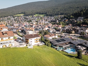 A residential area with houses, a swimming pool, and a hilly backdrop.