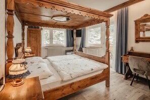 A wooden four-poster bed with a matching headboard, a desk with a chair, and a window with curtains. - Garni Toni (Castelrotto)