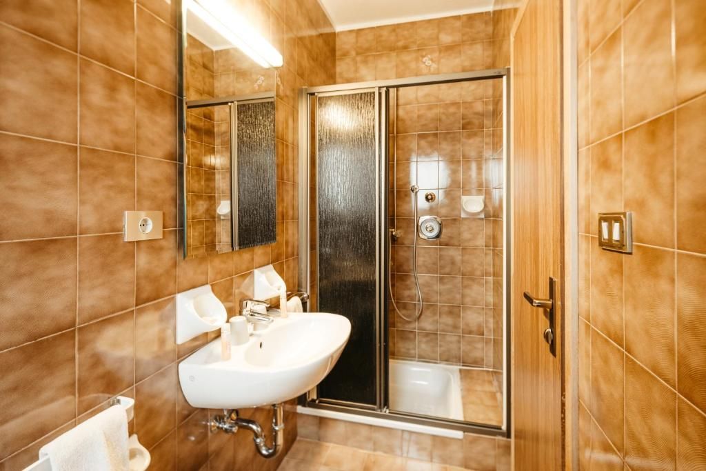 Un baño con un lavamanos blanco, cabina de ducha con vidrio y un espejo.