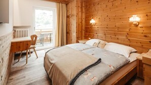 A wooden-paneled room with a bed, a desk, and a chair.