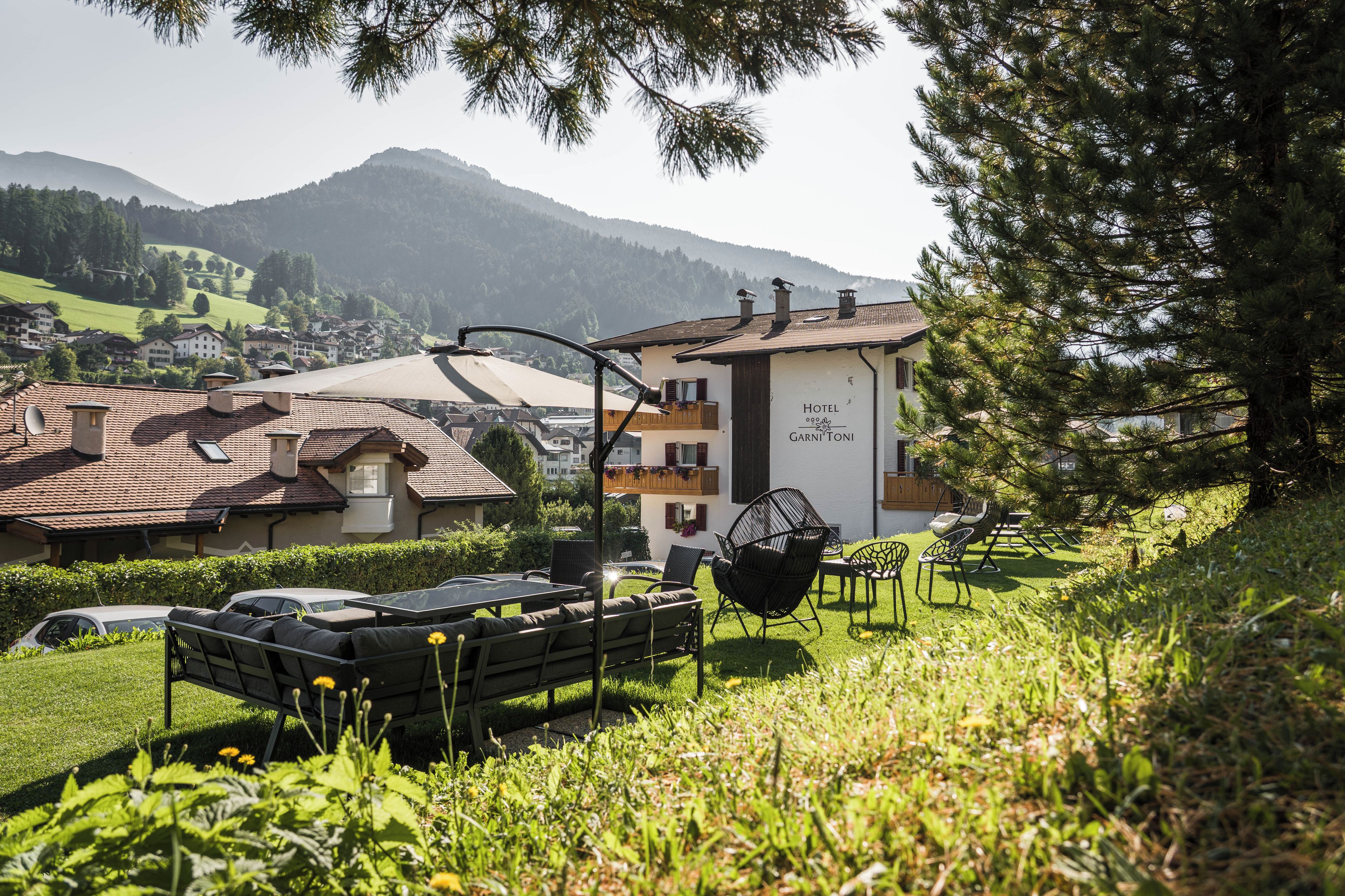 Un hotel con terraza, mobiliario exterior y vistas a la montaña.