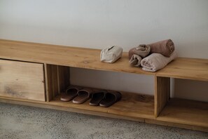 A wooden bench with a shelf, a pair of slippers, and a rolled-up towel. - SEN House Hoi An - 2 Bedrooms with Pool, Kitchen and Rooftop (Hoi An Tay)