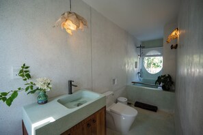 Ein Badezimmer mit einem Waschbecken, Toilette und einem Fenster.