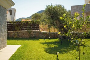 A well-maintained lawn with a stone wall and a tree with green leaves. - Villa Curreli – Authentic Sardinian Charm (Sardegna)