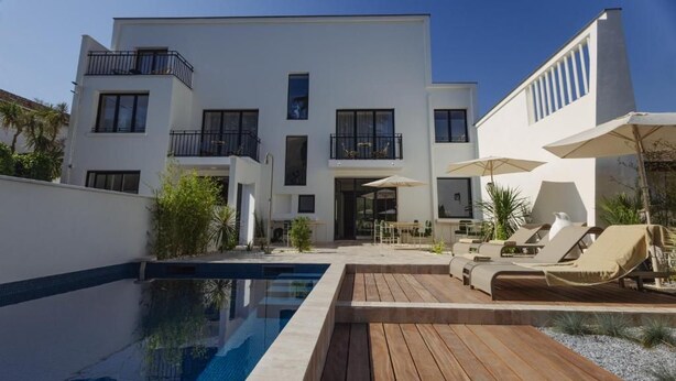 A modern two-story building with a swimming pool, outdoor seating, and a covered patio area. - L ODE A PIERRE (DAX)
