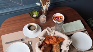 A breakfast setting with a wooden table, a bowl of fruit, a croissant, a teapot, and a cup of tea. - L ODE A PIERRE (DAX)