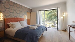 A bedroom with a bed, bedside table, and a view of the outdoors. - L ODE A PIERRE (DAX)
