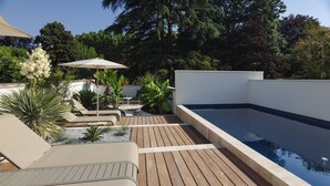 A rooftop pool area with wooden decking, lounge chairs, and a small table with an umbrella. - L ODE A PIERRE (DAX)