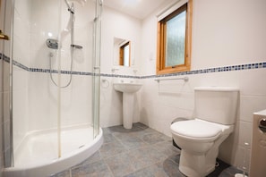 A bathroom with a glass-enclosed shower, a pedestal sink, and a toilet. - Sidlaw (Dundee)
