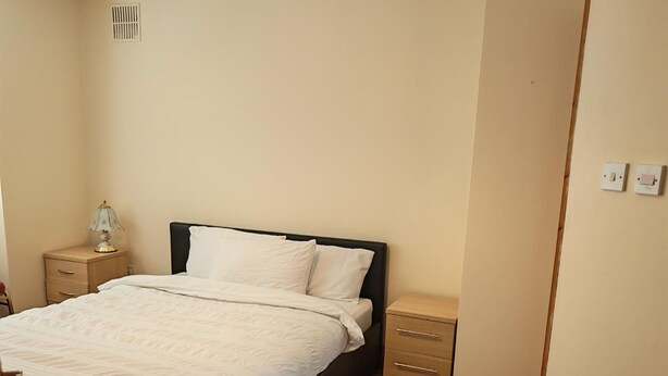 Ein Schlafzimmer mit einem Bett, Nachttischen, einem Teppich und einer Pendelleuchte.