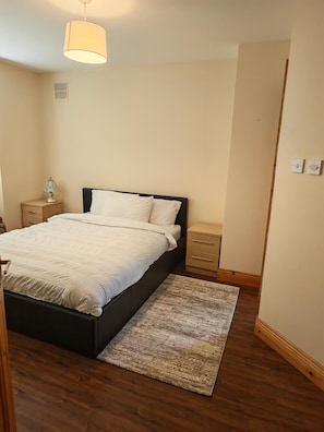Ein Schlafzimmer mit einem Bett, Nachttischen, einem Teppich und einer Pendelleuchte.