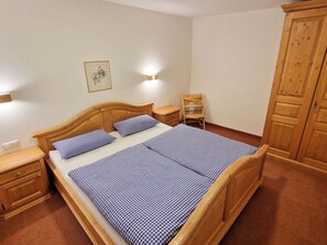 Een slaapkamer met een houten bed, twee nachtkastjes, een stoel en een garderobe.