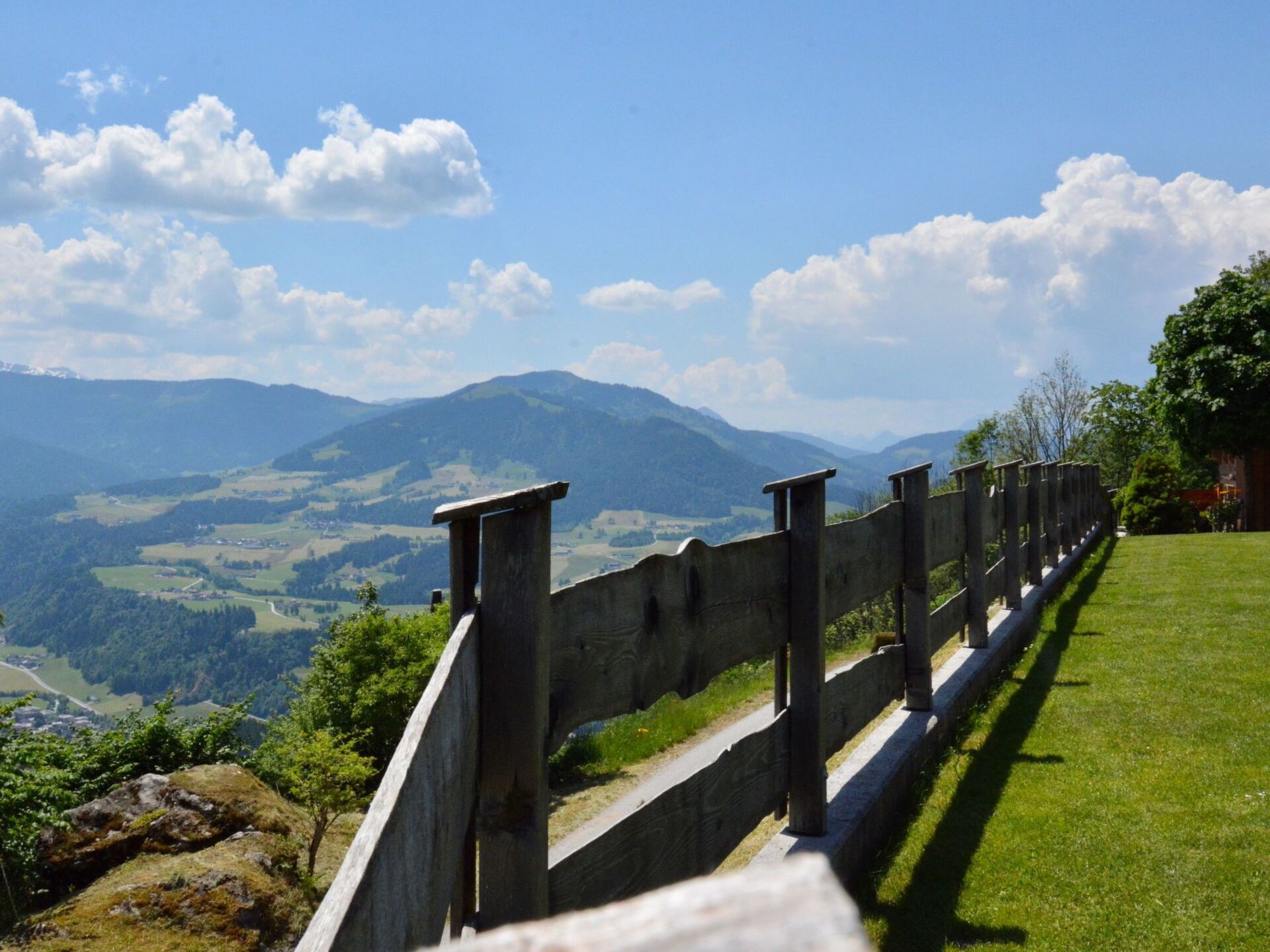 Una valla de madera con vista a un valle y montañas a lo lejos.