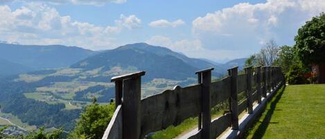 Una valla de madera con vista a un valle y montañas a lo lejos.