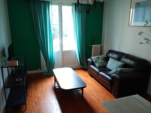 A living room with a black leather sofa, a wooden coffee table, and a glass cabinet. - Charming one-bedroom apartment near Bois de Vincennes (Fontenay-sous-Bois)