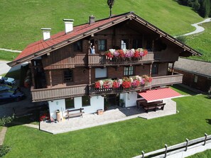 Un chalet en bois doté d’un balcon, d’un auvent rouge et de jardinières fleuries.