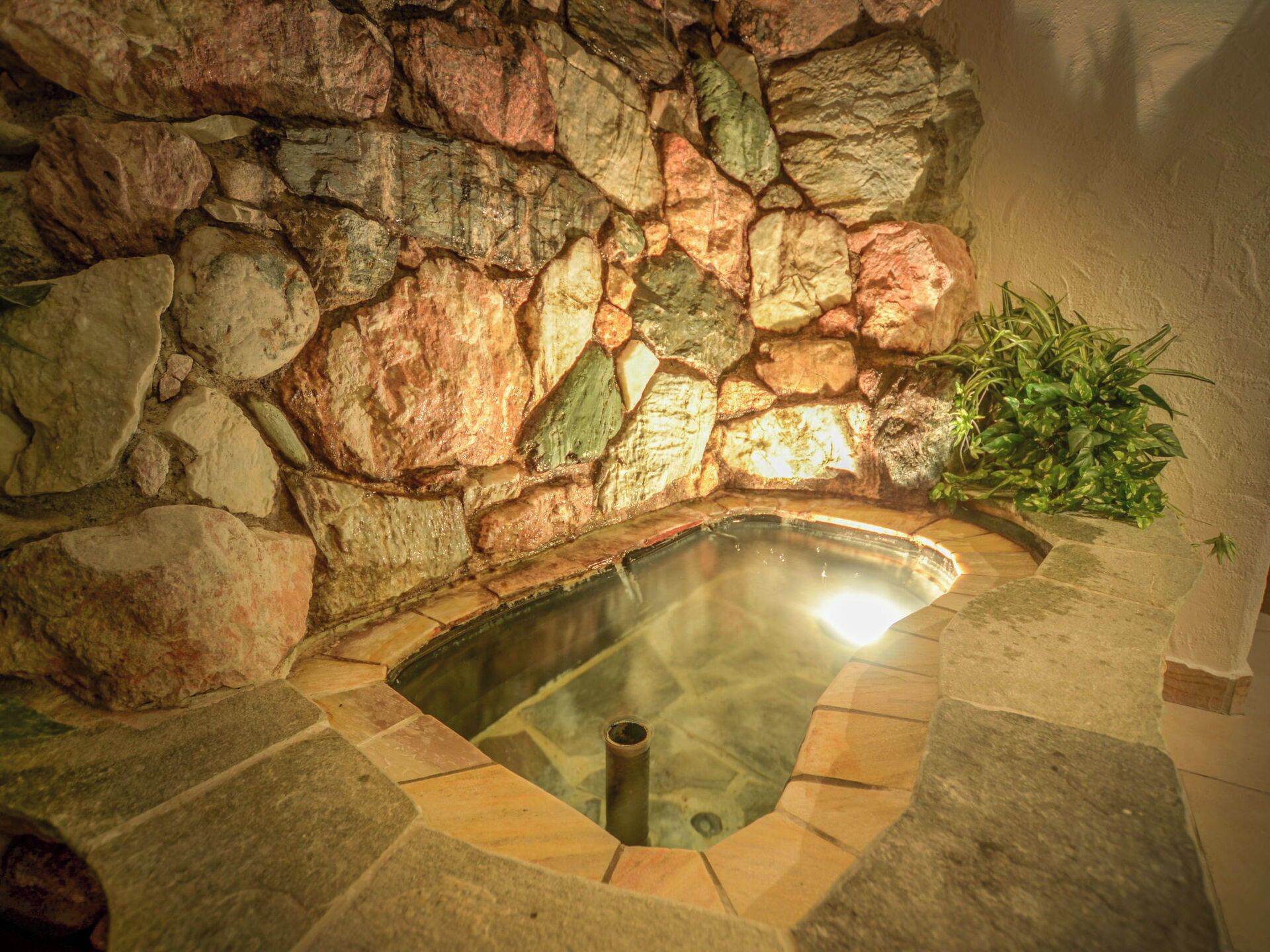 A stone wall surrounding a hot tub with a clear view into the water.