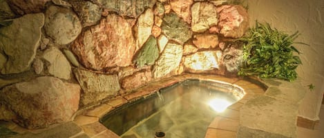 Un muro de piedra rodea una bañera de hidromasaje con vista despejada al agua.