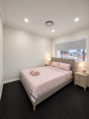 Quarto com cama, abajures, janela e vista exterior.