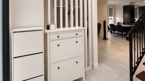 A modern interior with a white storage unit, a staircase, and a dining area. - Luxury Family Retreat in Chipping Norton (Chipping Norton)