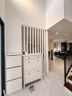 Um interior moderno com um armário branco, uma escada e uma área de jantar.