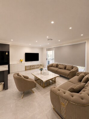Uma sala de estar moderna com sofá, mesa de centro e televisão de tela plana na parede.