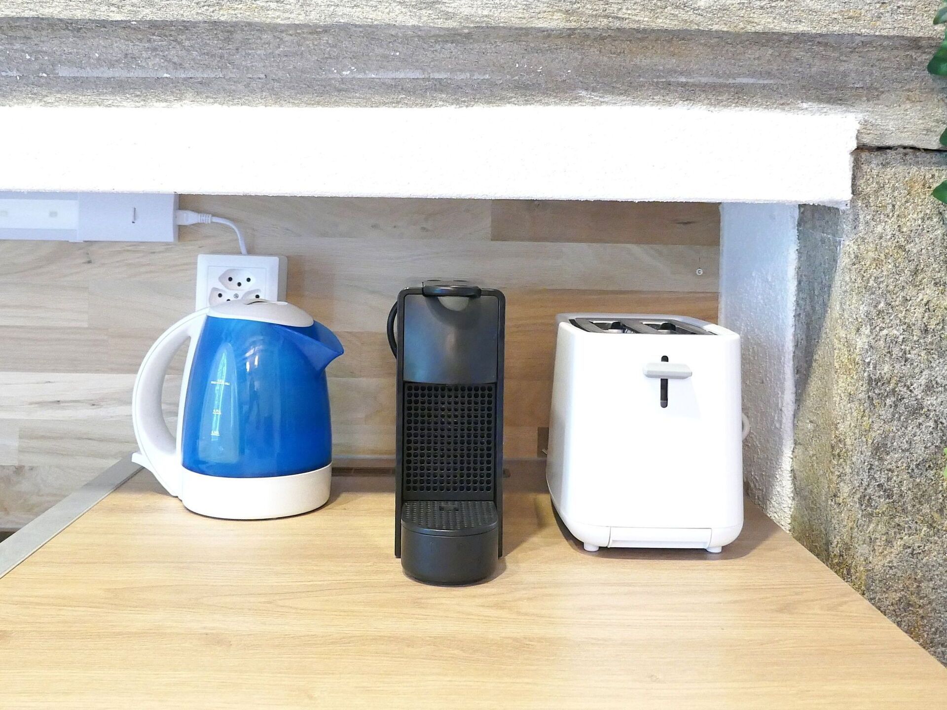 Uma bancada de cozinha com uma chaleira, um aquecedor portátil e uma torradeira.