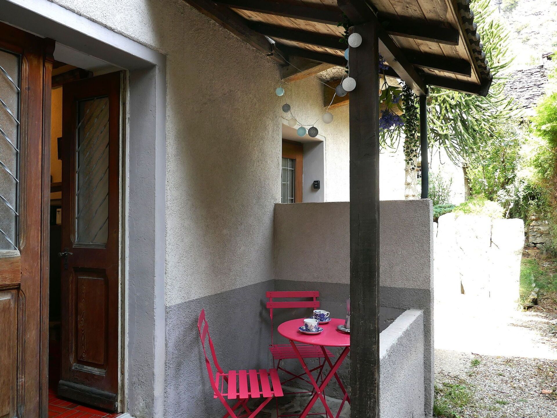 Un espace patio avec une table et des chaises, une porte et un mur en pierre.