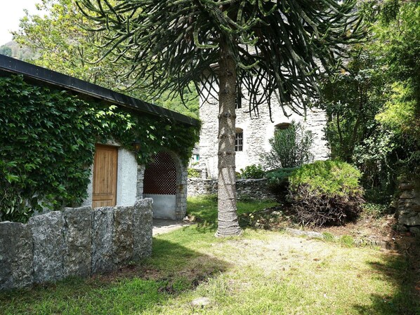 Un edificio in pietra con una porta in legno e un portico coperto da viti.